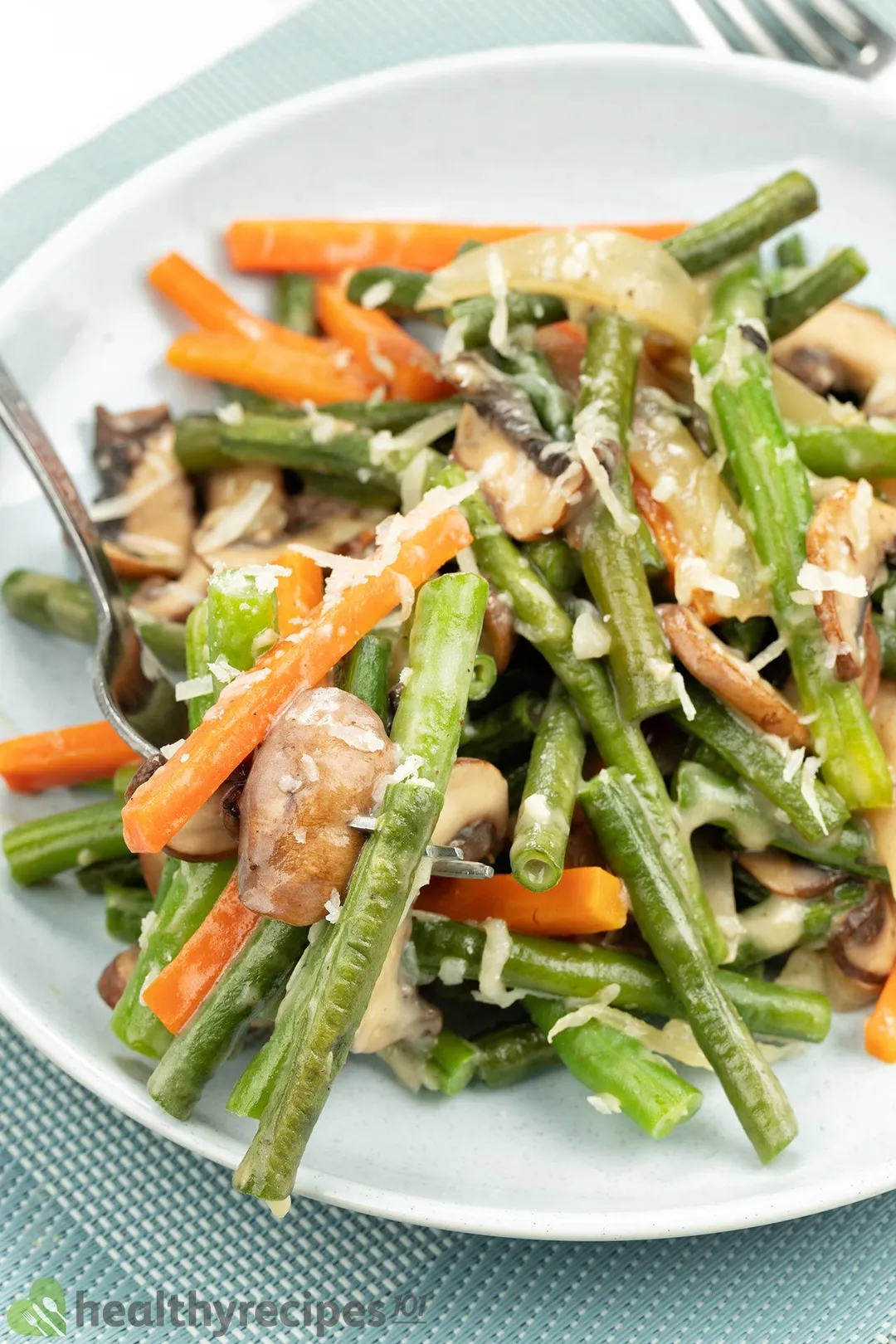 A plate of sauteed green beans, julienned carrots, and mushrooms.