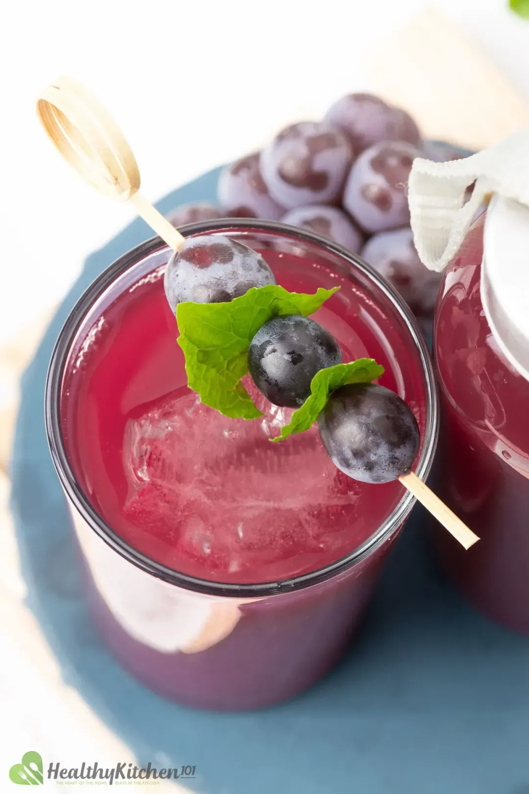 Shot from above, a glass full of grape juice and apple cider cocktail garnished with a grape skewer and a grape vine