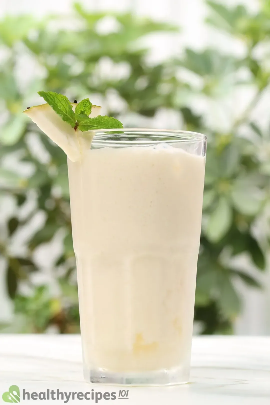 A tall glass of iced soursop juice, garnished with mints and a soursop wedge on the rim