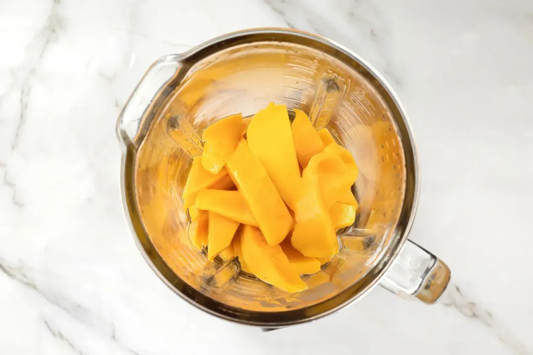 Sliced mangoes in a blender
