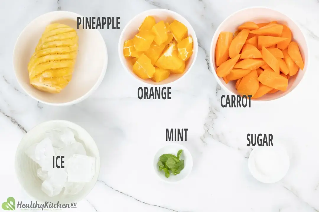 Ingredients in separate bowls: a peeled pineapple, peeled oranges, chunked carrots, ice cubes, mints, and sugar