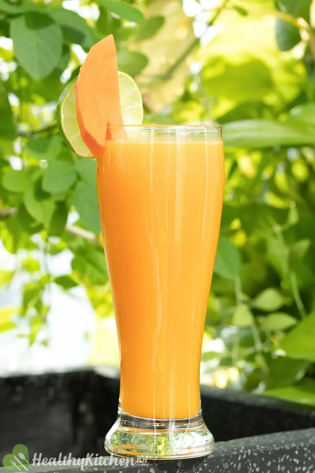 A tall glass of carrot mango drink out in the open