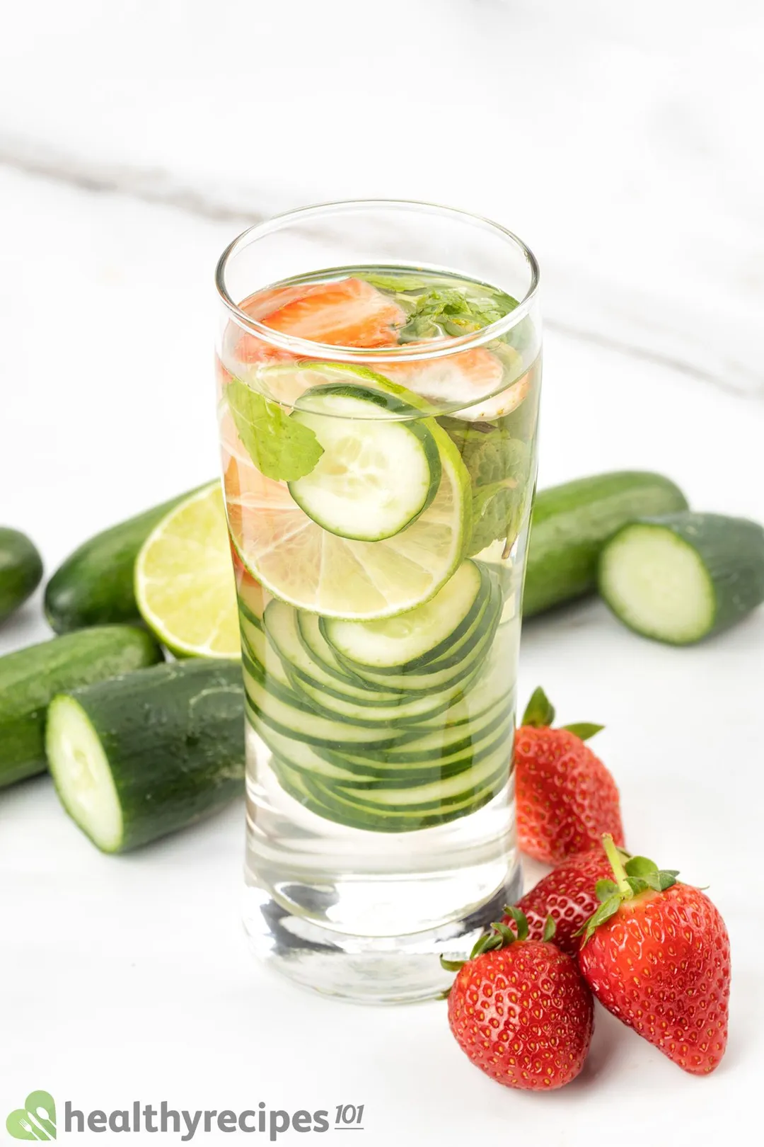 a glass of Cucumber Strawberry Water decorated by strawberries and cucumber