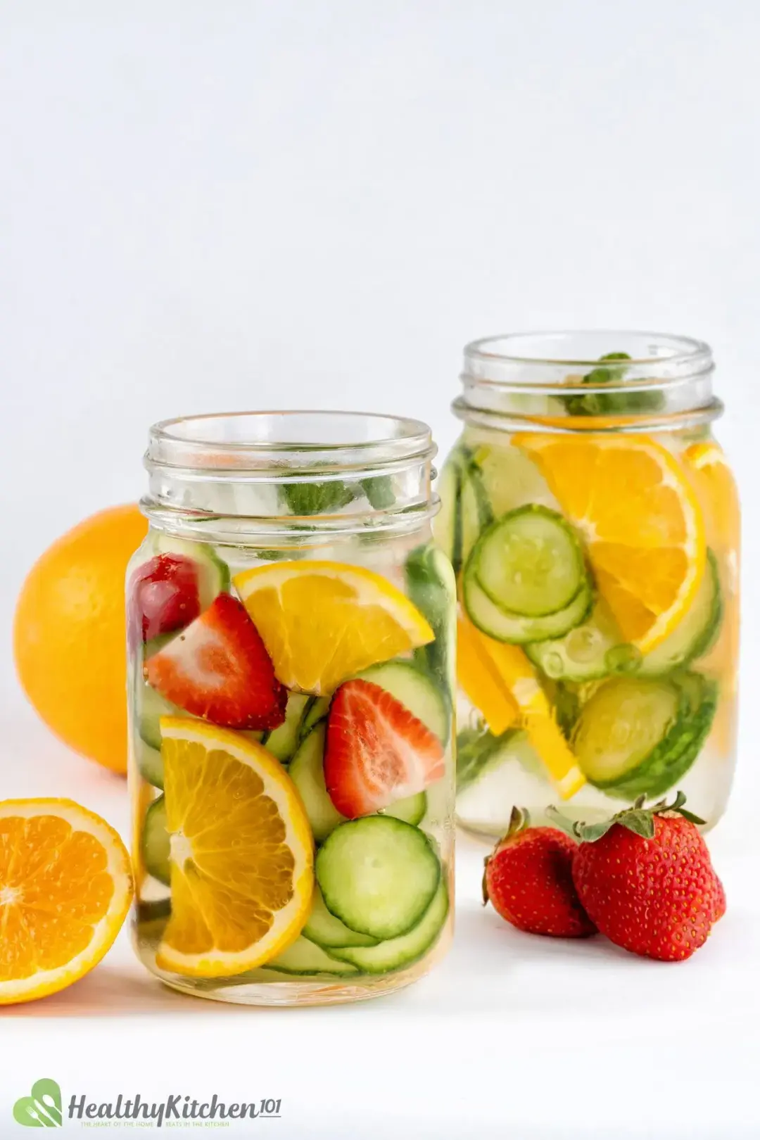 Two jars filled with cut up fruits placed next to strawberries