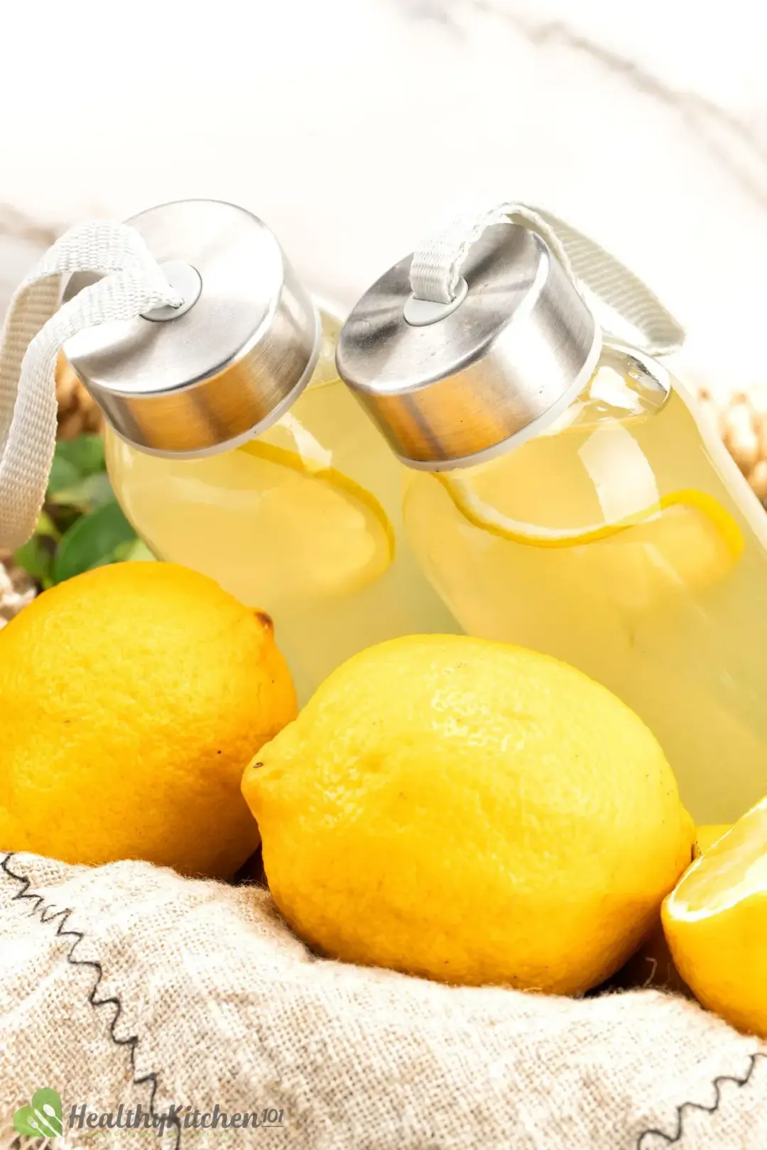 Two bottles of lemonade sitting on top of some whole lemons