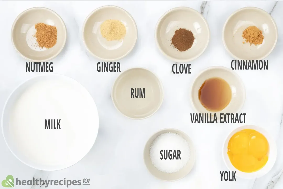 Ingredients in separate bowls: Ginger, clove powder, cinnamon powder, rum, milk, vanilla extract, sugar, and beaten yolks