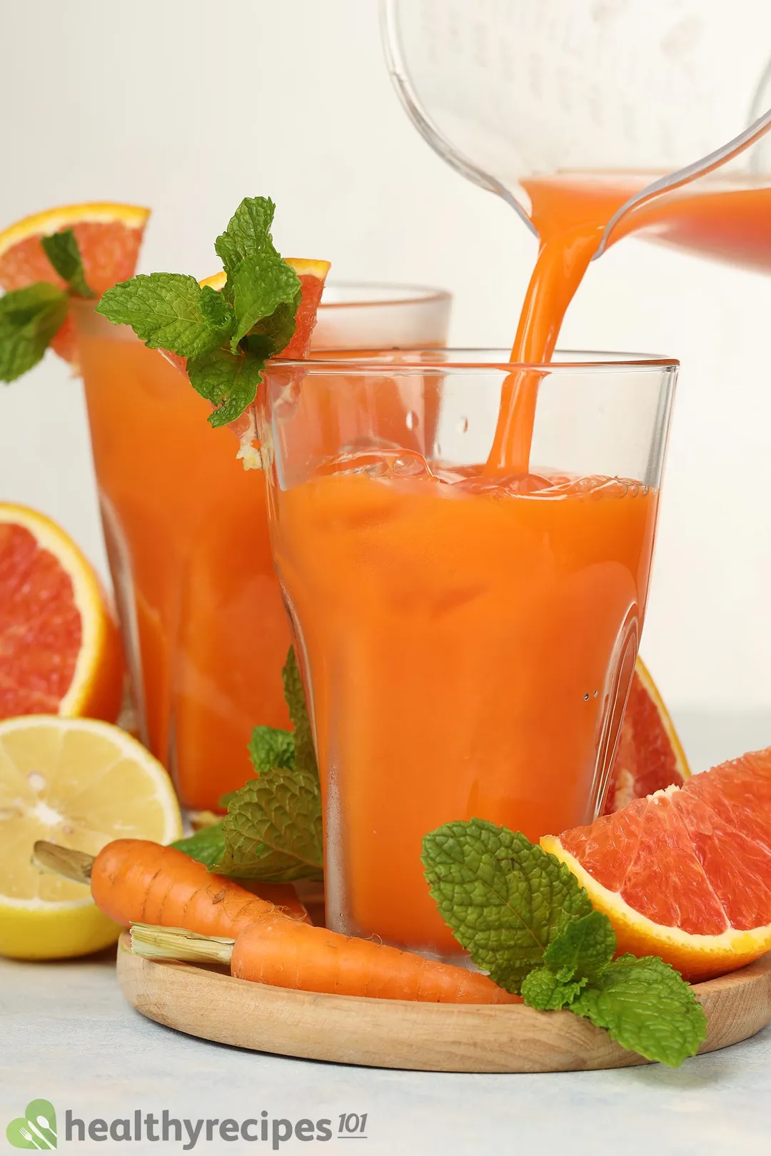 pouring grapefruit carrot juice from a pitcher into two glasses