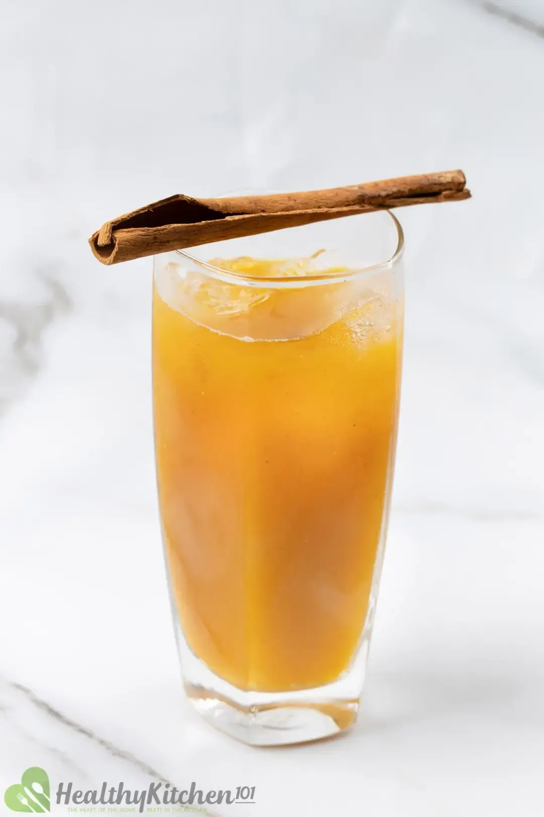 A glass of iced pumpkin juice with a cinnamon stick on top