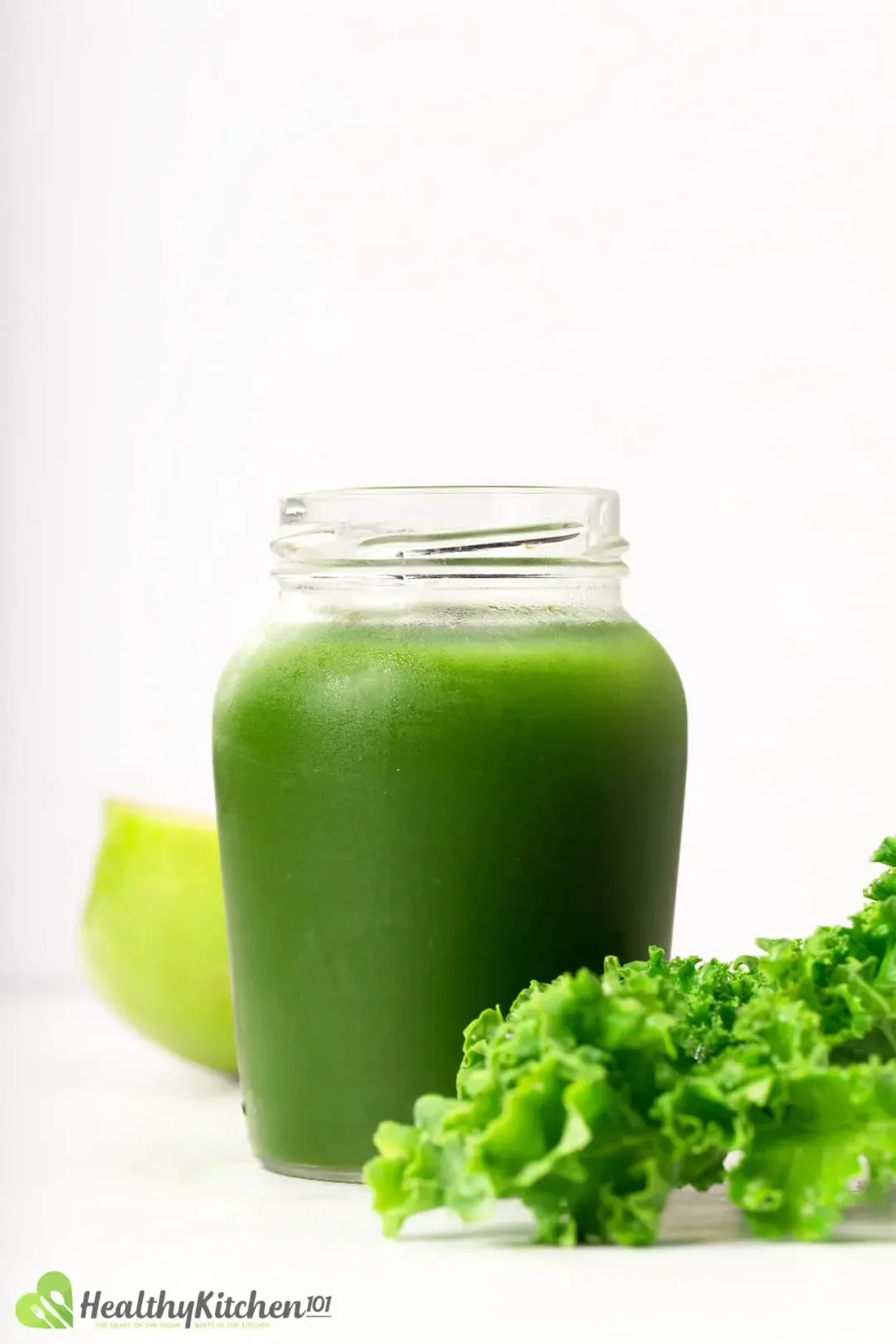A cool jar holding green vegetable juice with a kale leaf on the side