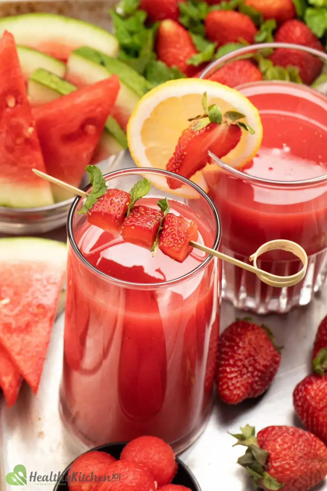 two glasses of strawberry watermelon juice decorated with strawberries and a slice of lemon