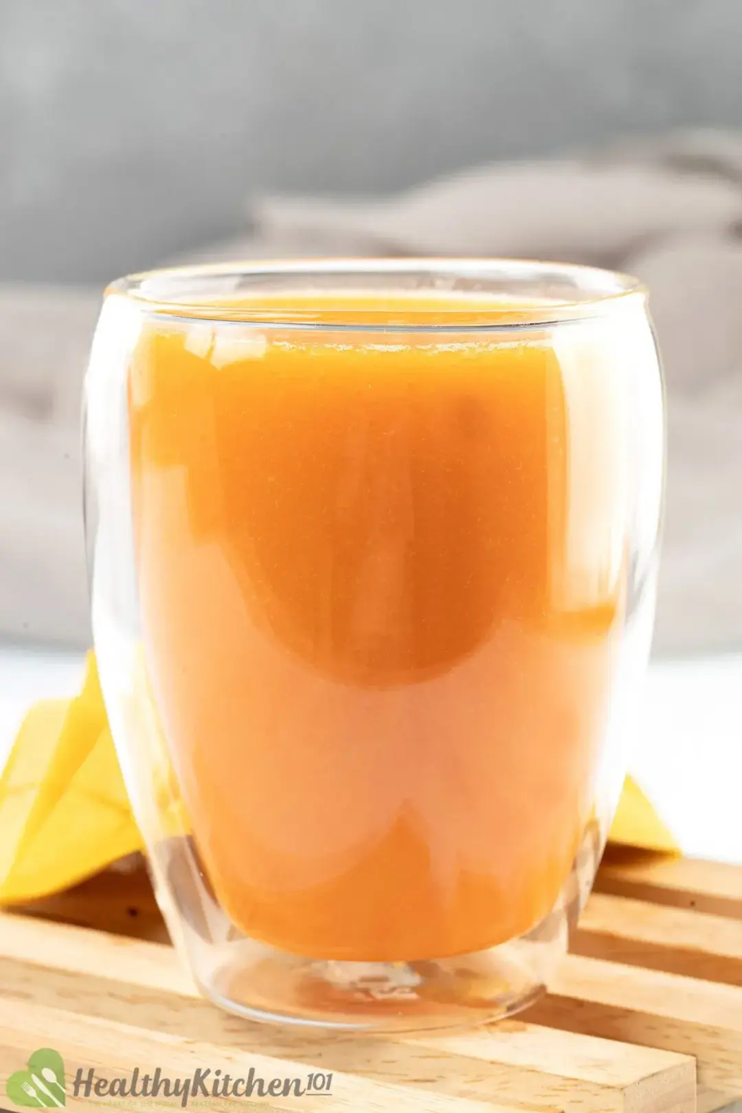 A short glass of carrot mango juice put on a wooden board