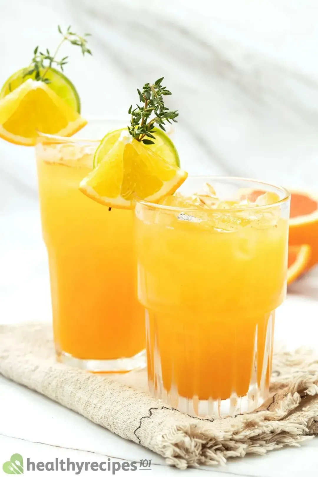 Two glasses of iced orange juice and gin cocktail garnished with citrus slices, and thyme sprigs