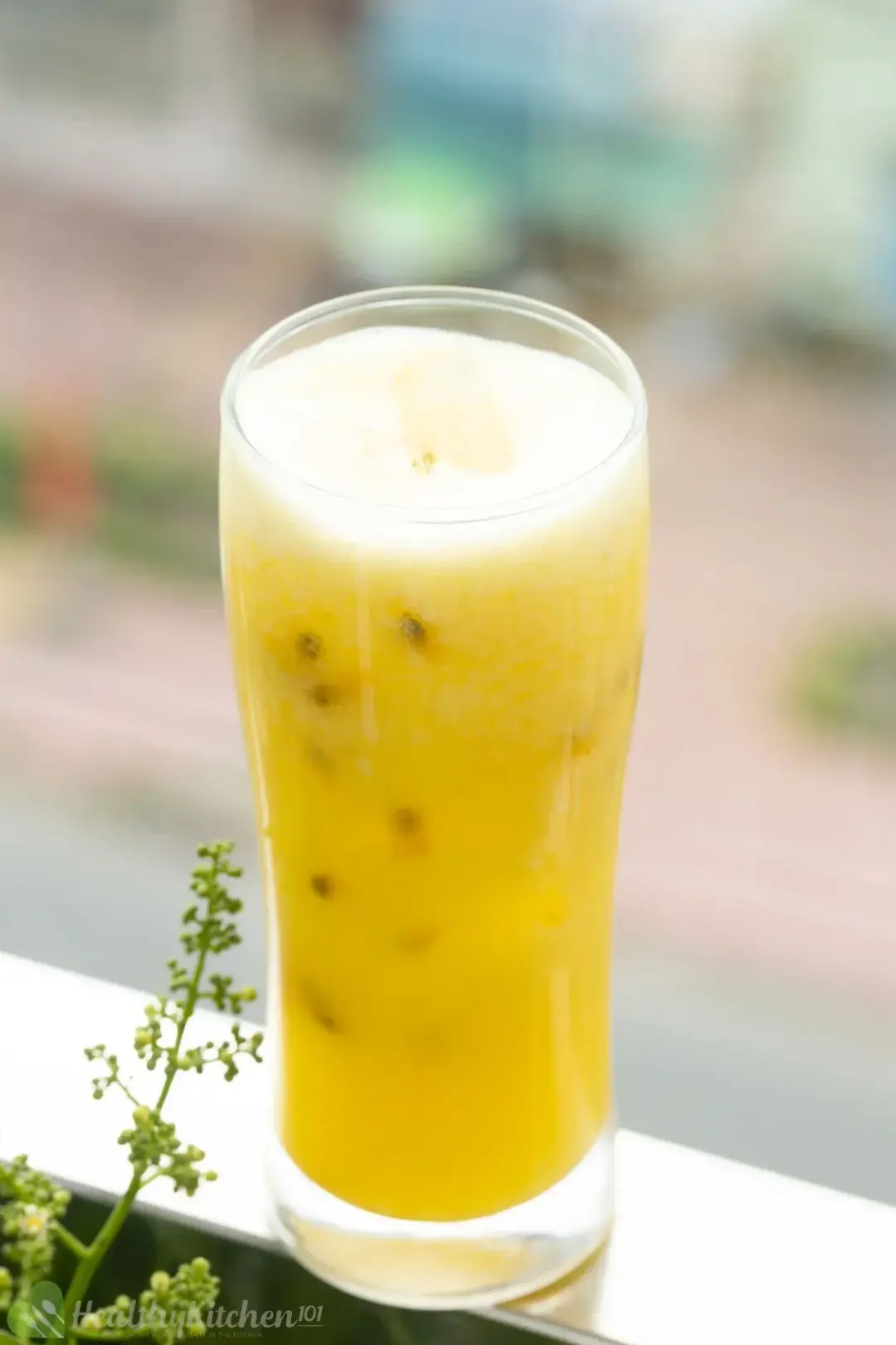 A glass of passion fruit blended with mango put near a window