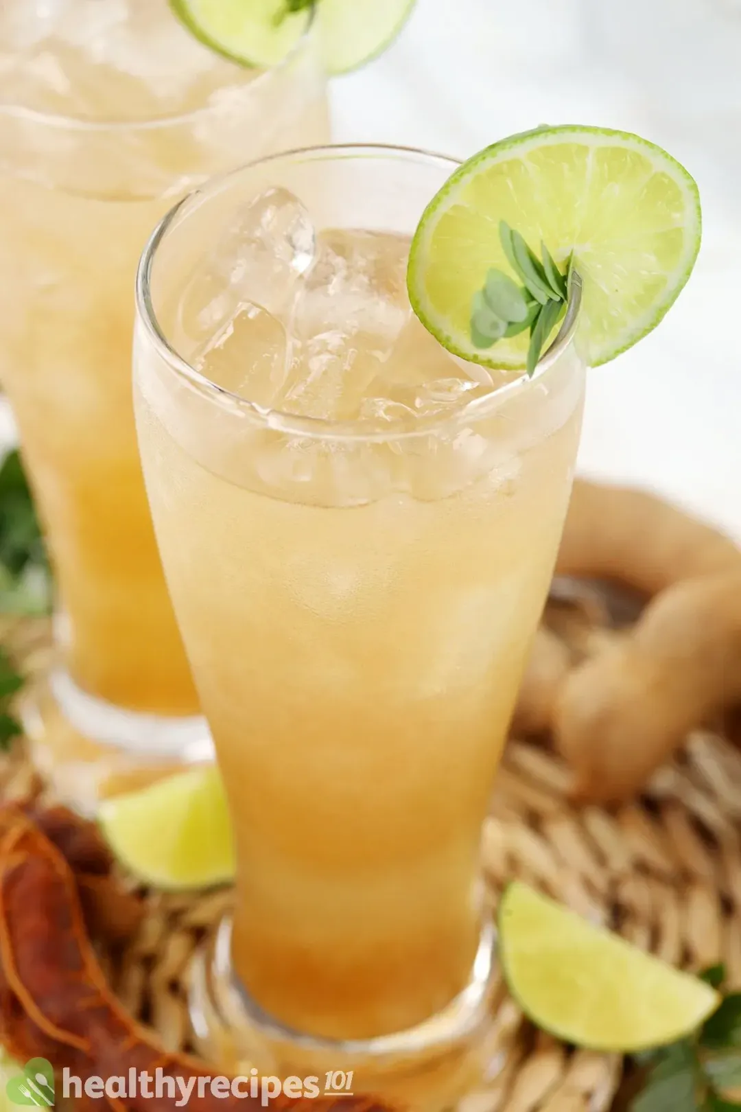 Two glasses of tamarind drinks with ice and lime slices on the brim as decoration