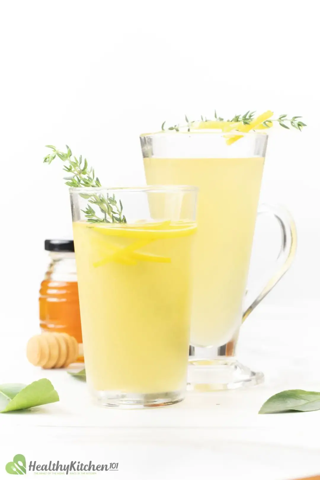 Two lemonade glasses with thyme sprigs and lemon peels inside