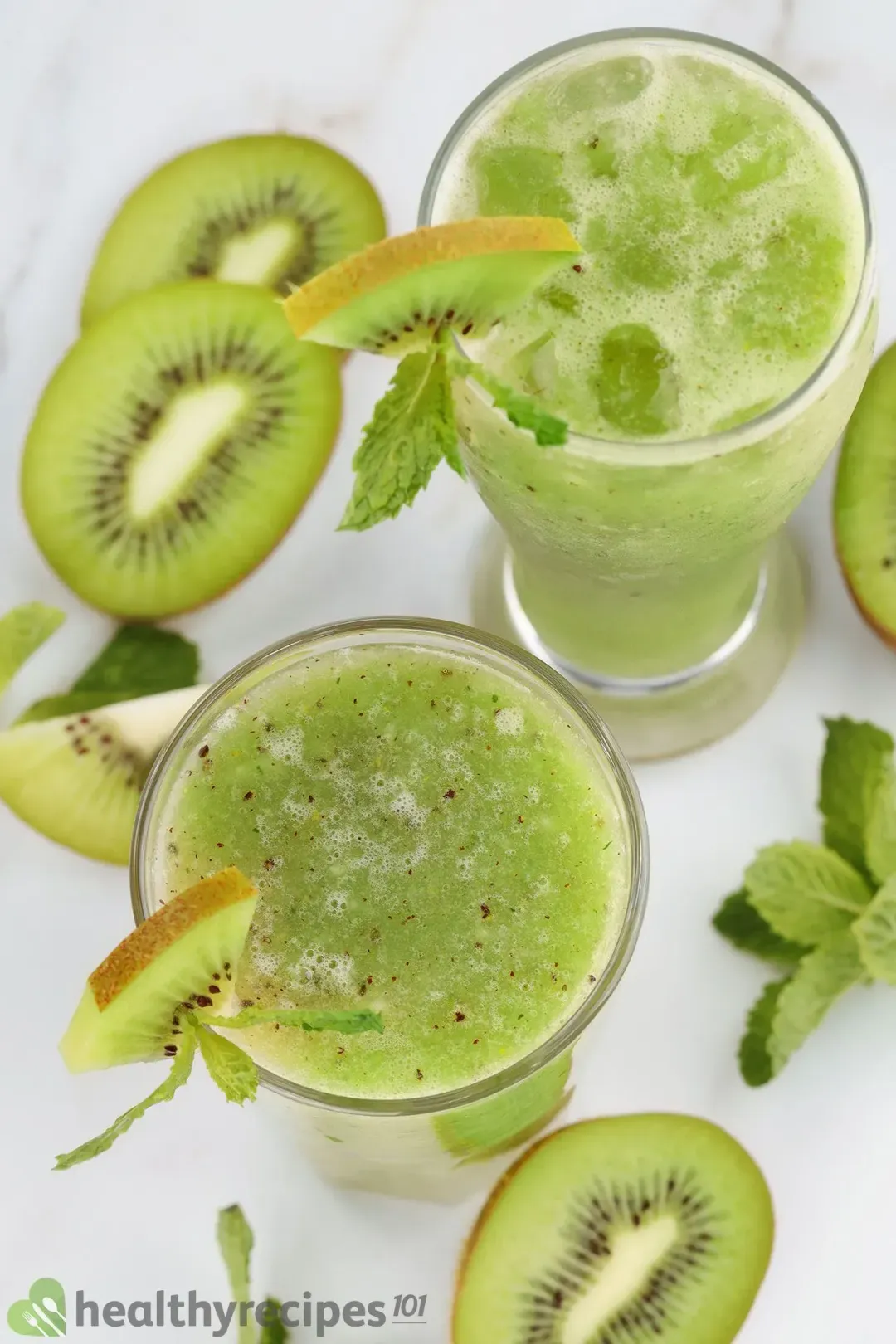 Two iced glasses of kiwi juice, garnished with lots of kiwis in different shapes