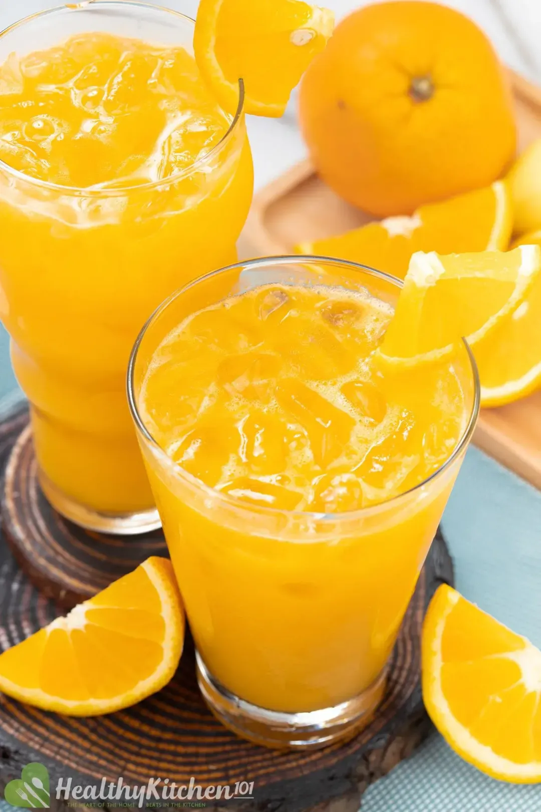 Two iced glasses of orange juice, garnished with lots of oranges in different shapes