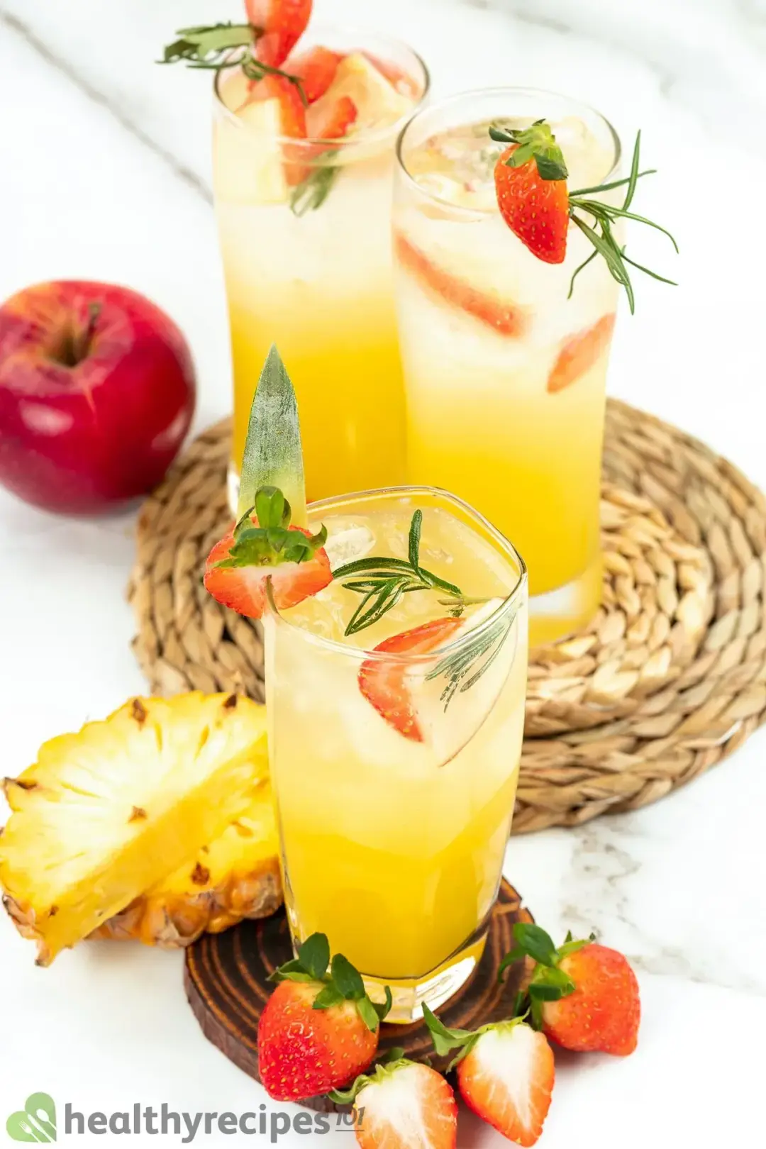 Three glasses of orange vodka cocktail put side by side, with sliced fruits all around as garnish