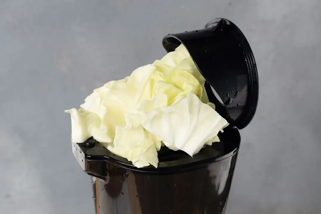 Some cabbages placed on top of a juicer's feeder