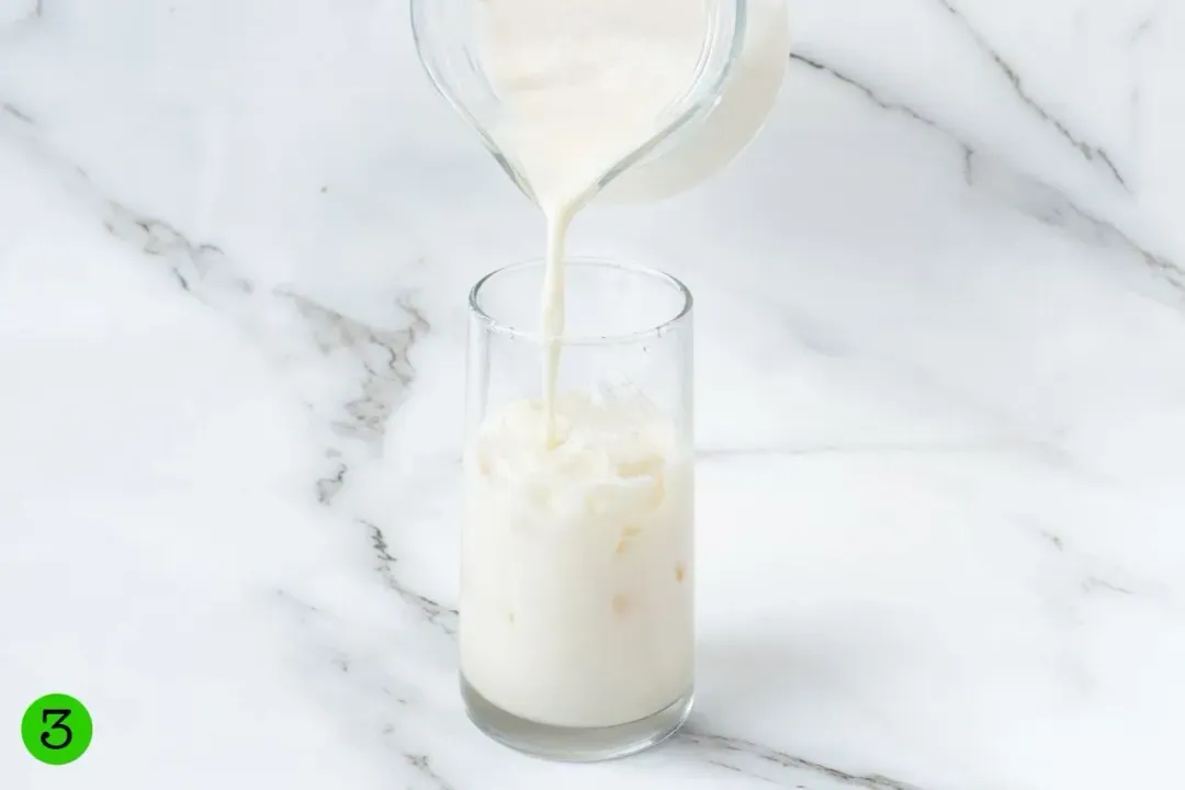 A pitcher of iced milk pouring into a glass