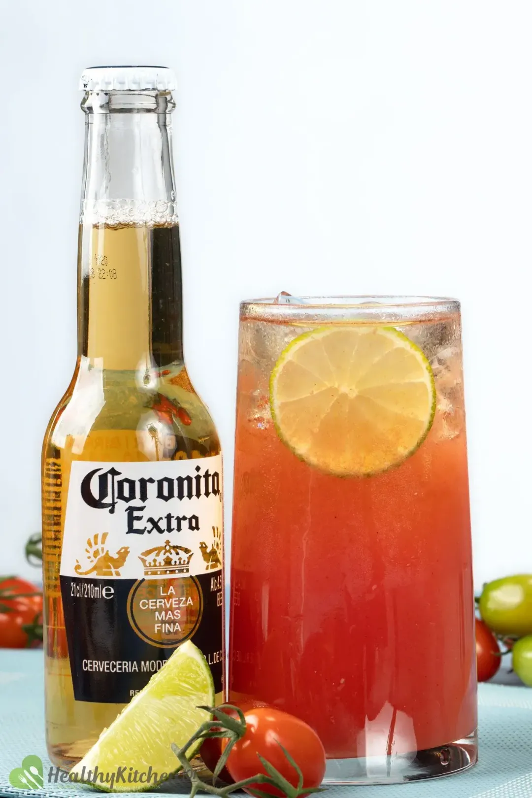 A beer bottle next to a tomato juice cocktail and some fruits