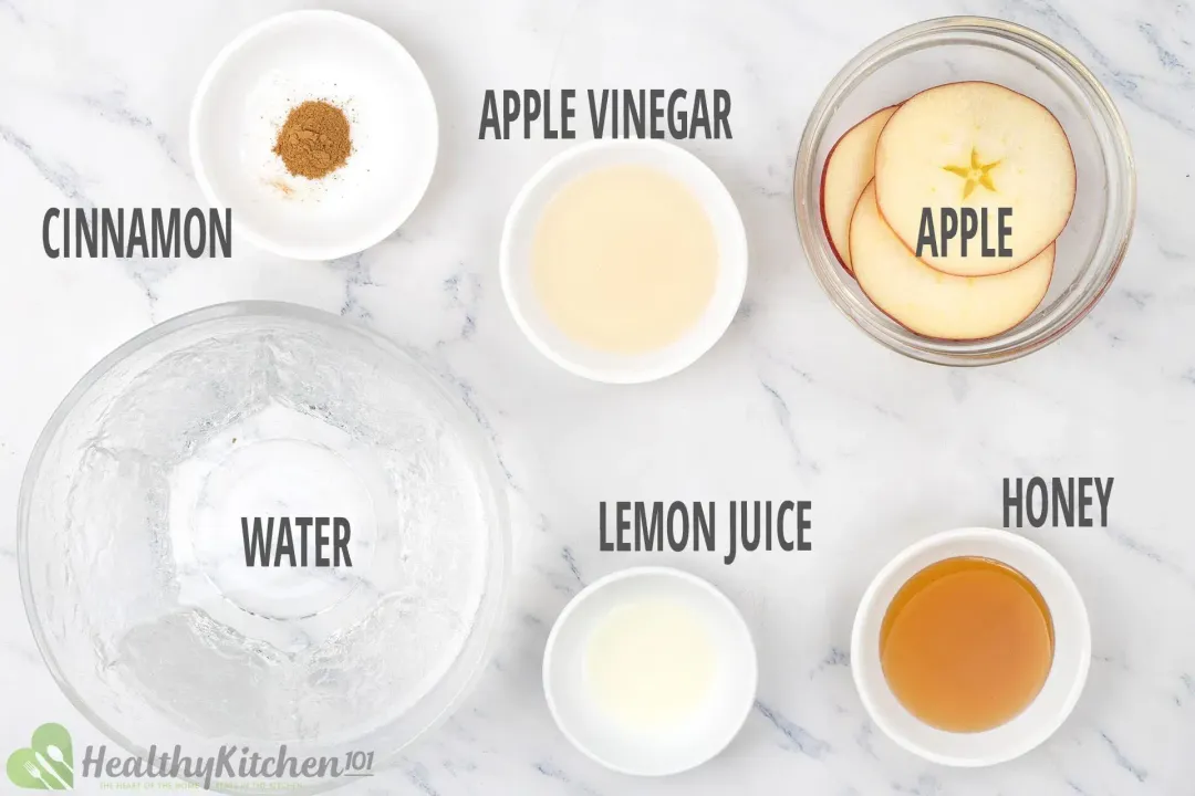 Bowls and plates of cinnamon powder, apple vinegar, apple slices, honey, lemon juice, and water