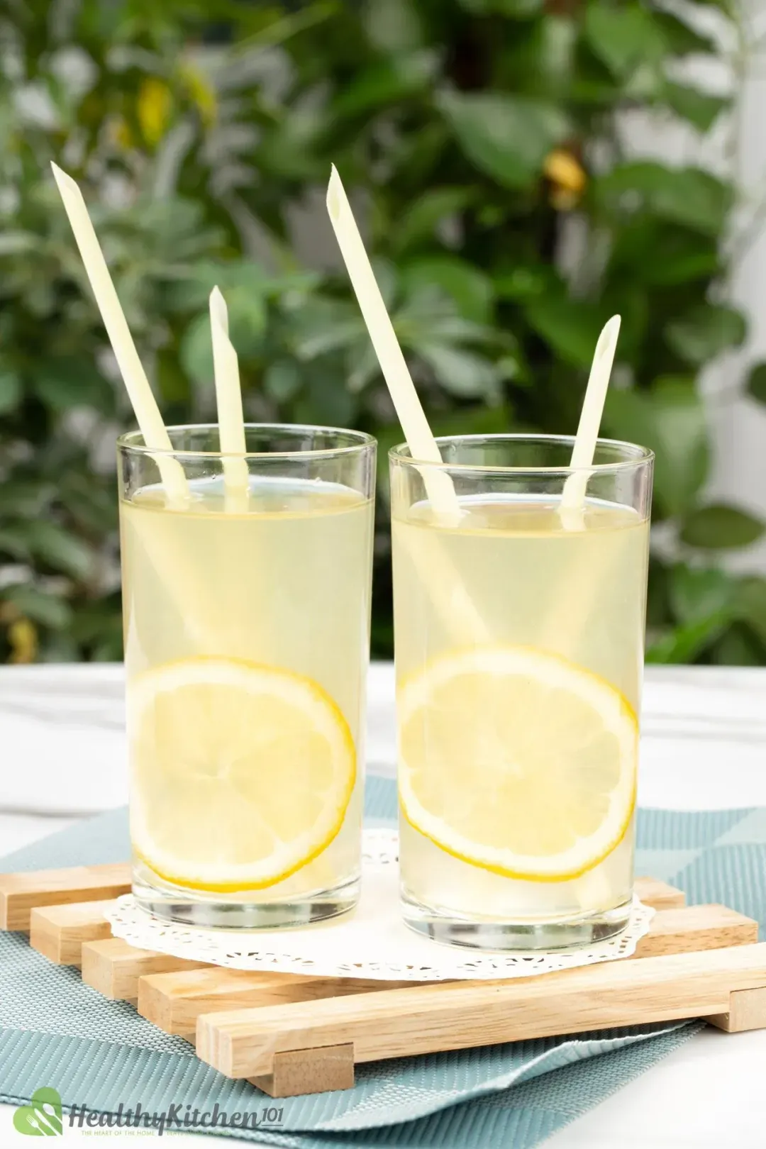 Two glasses of lemon juice and apple cider drinks, with straws and lemon wheels inside