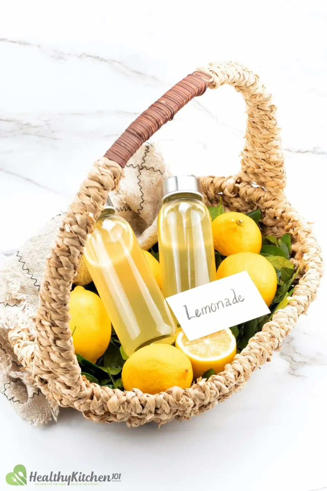 Two lemonade bottles and whole lemons inside a cute bamboo basket