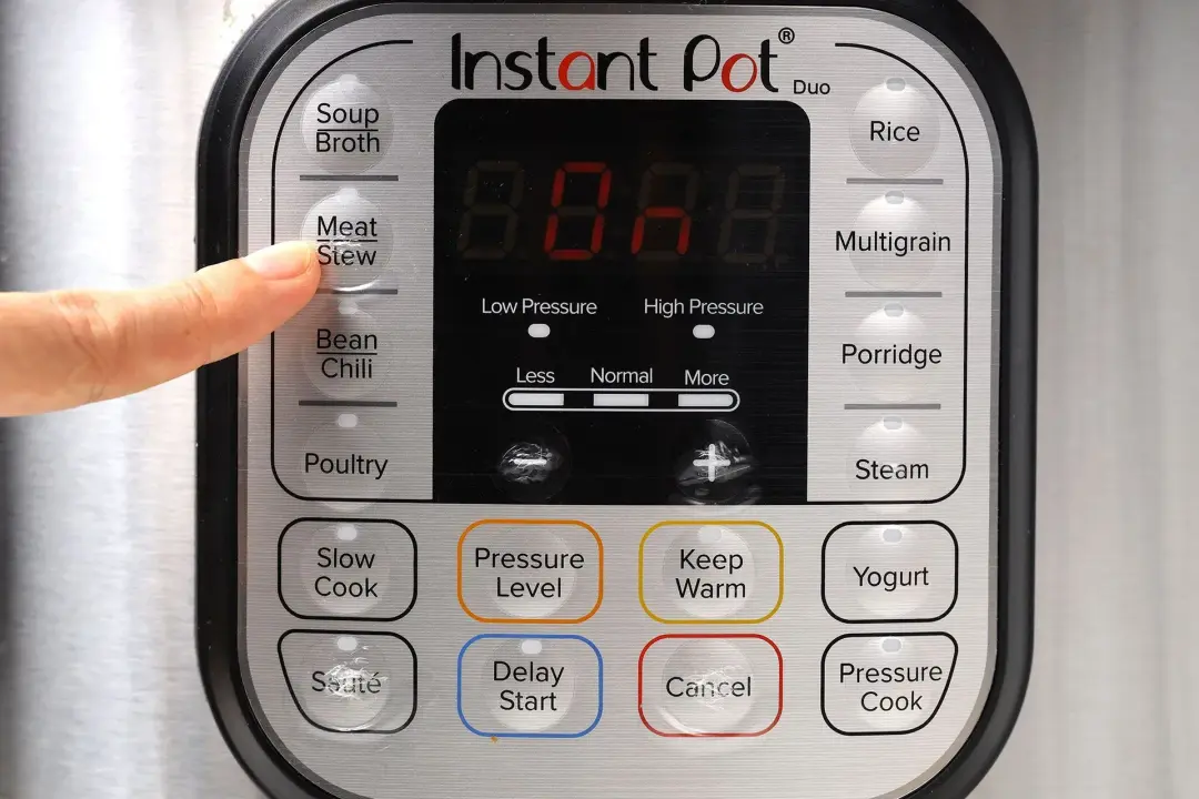 A hand pointing at the meat/stew function of an Instant Pot