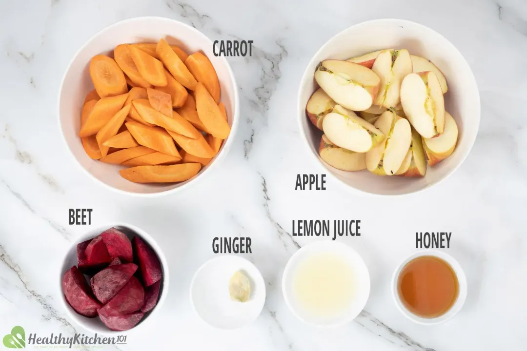 Ingredients in separate bowls: sliced carrots, apple quarters, beetroot wedges, a ginger knob, lemon juice, and honey