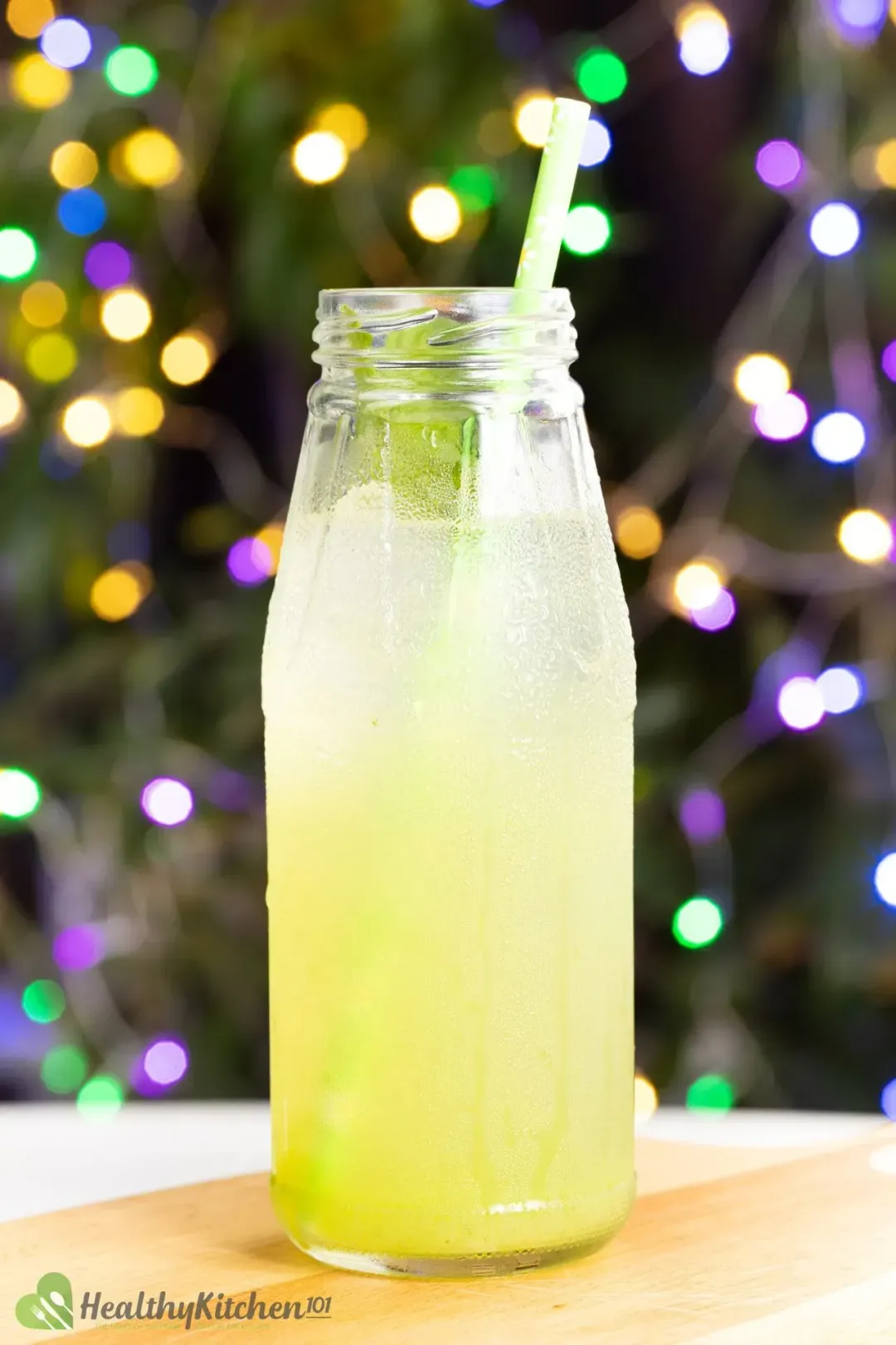 A jar of cucumber lime juice with a straw taken in front of a Christmas tree