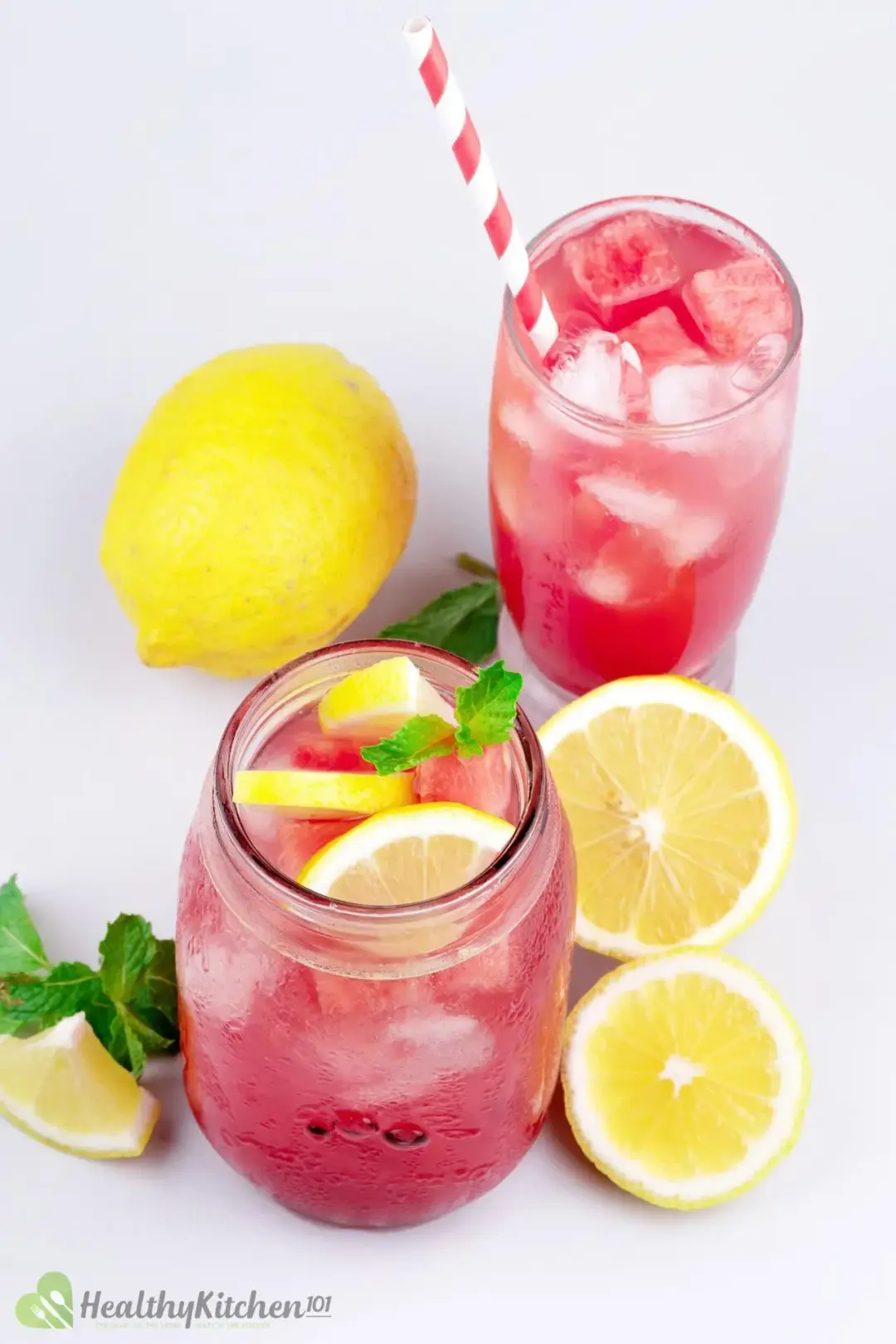 two glasses of watermelon juice and lemon with a pink-striped straw and a jar of watermelon juice and lemon topped with three lemon slices and mint leaves