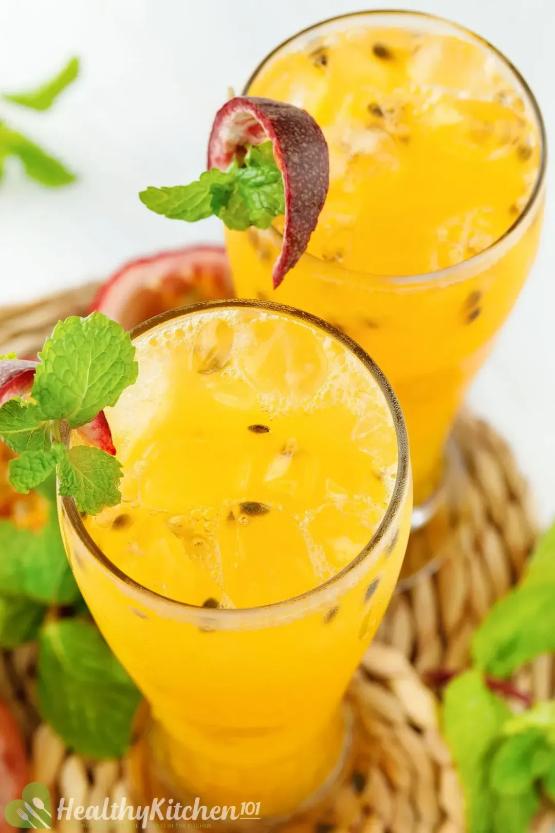 Two glasses of passion fruit juice with seeds and ice, garnished with mints