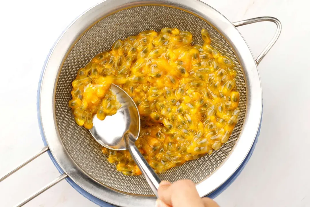 Passion fruit pulp and seeds inside a sieve