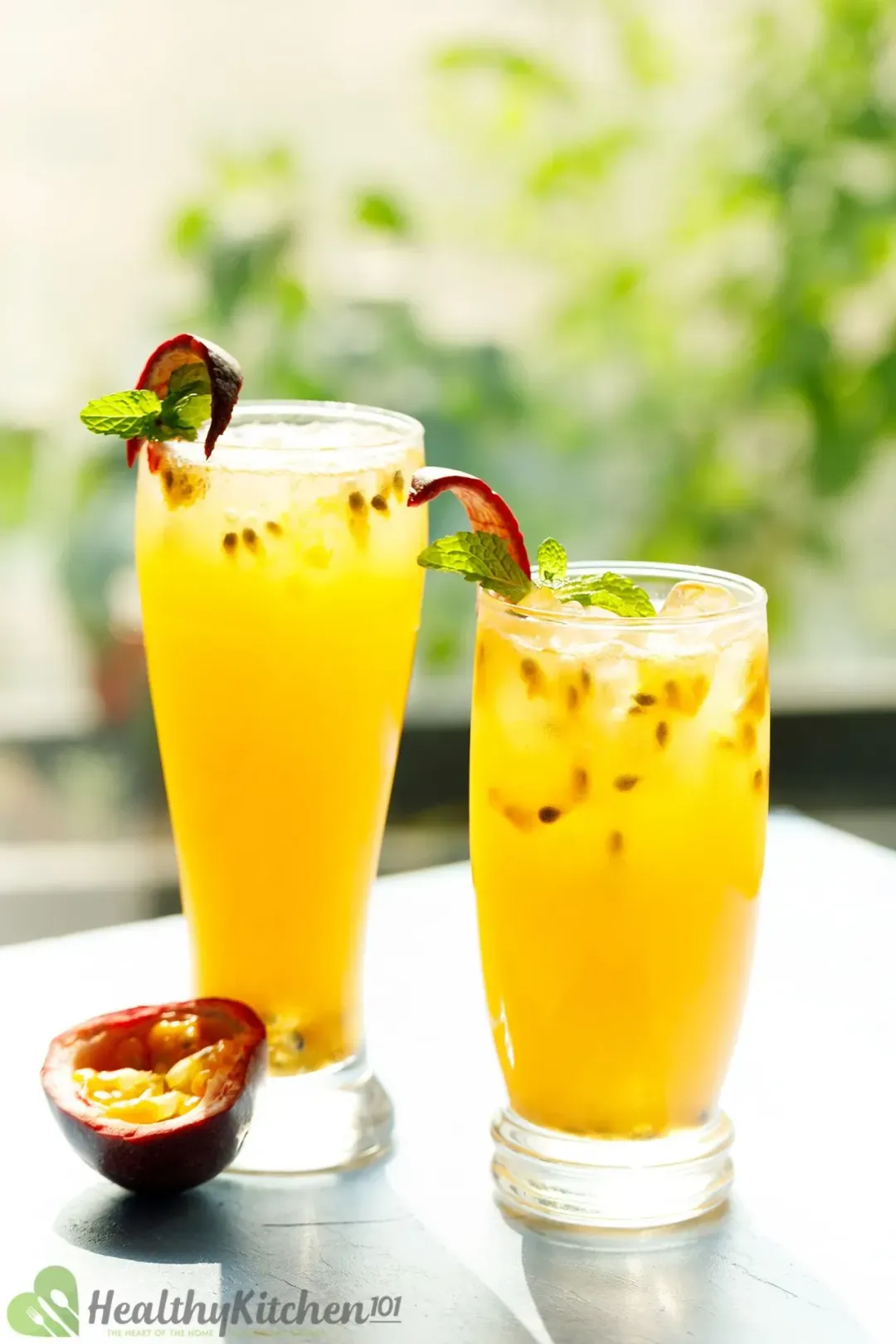 Two glasses of passion fruit juice, with ice and passion seeds inside