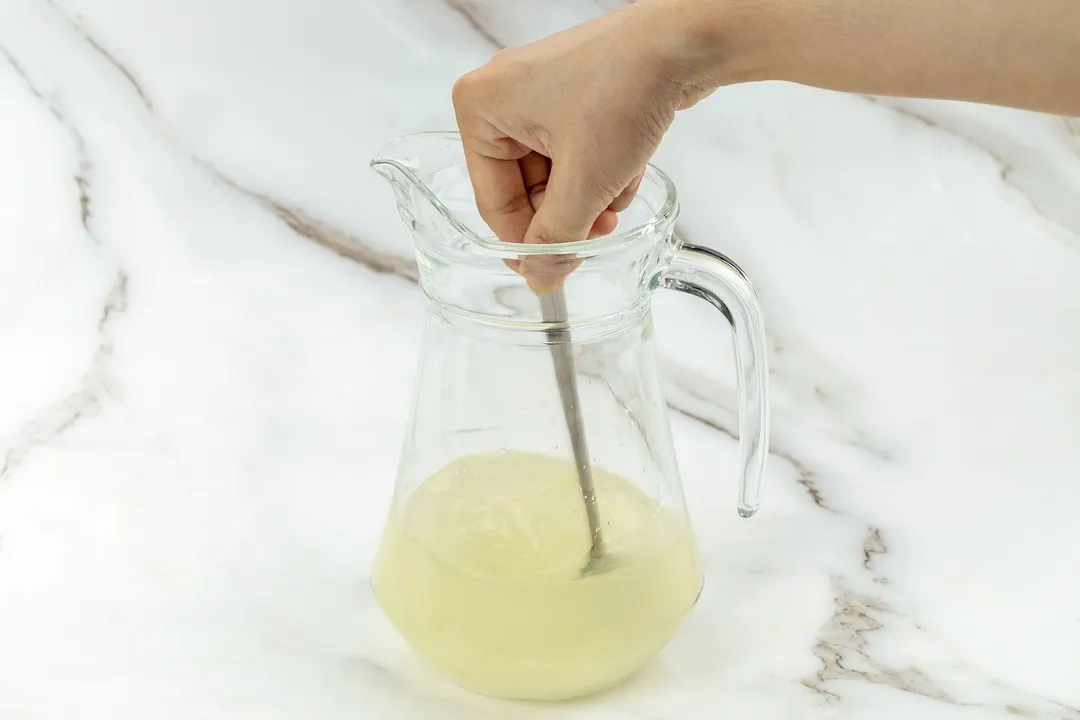 whisking a spoon on a pitcher of juice