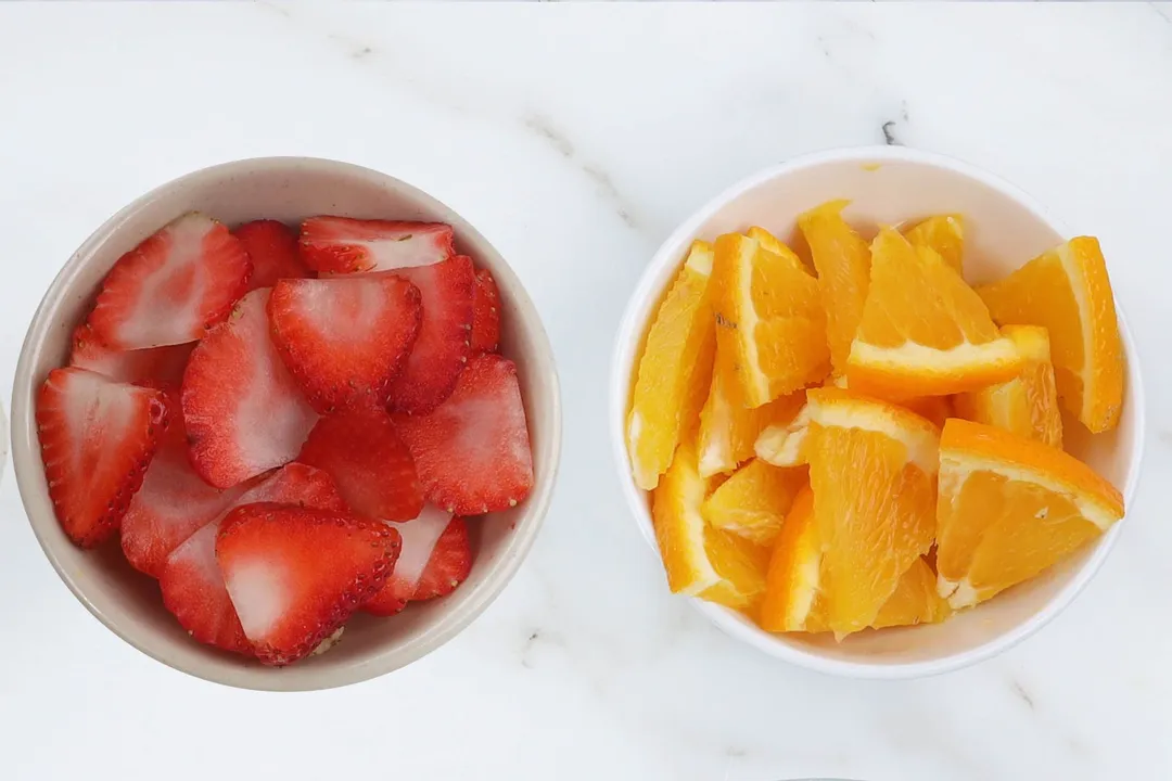 two small bowl of sliced strawberry and sliced orange