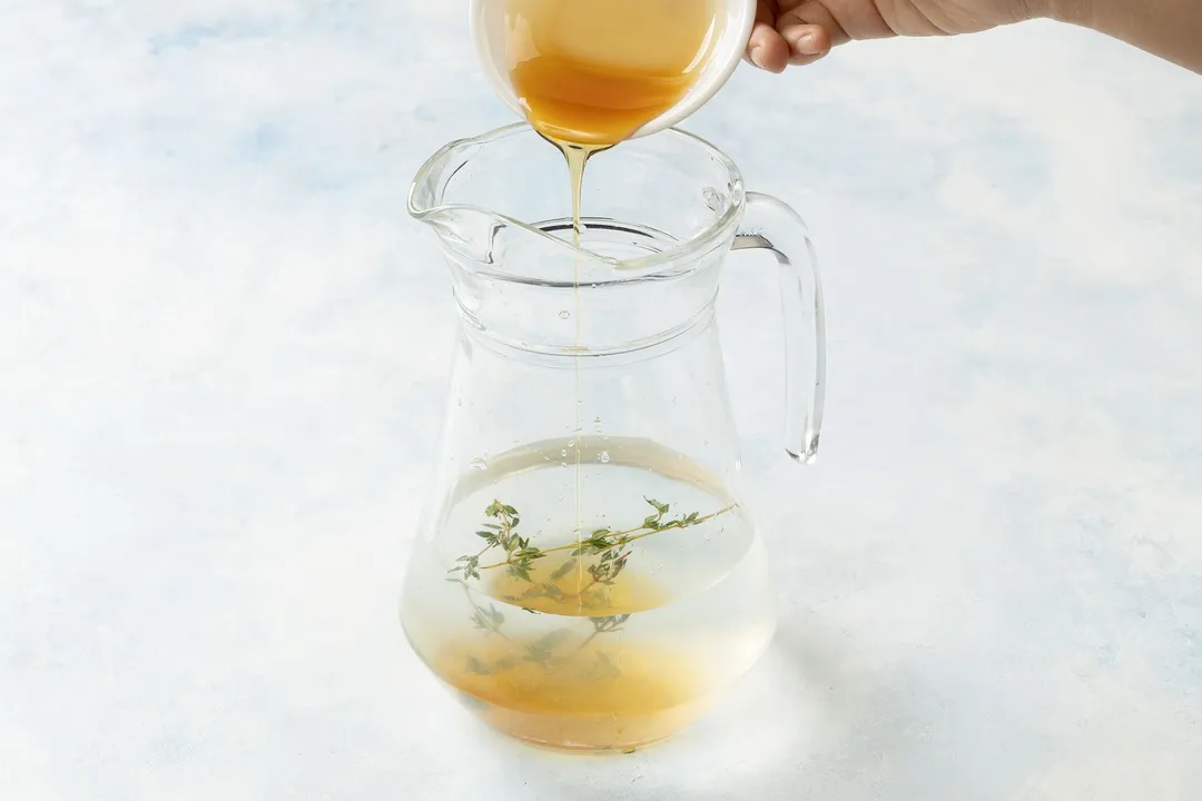 pouring honey from a small bowl to a glass jar