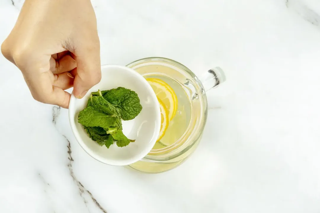 Holding a bowl of mint leaves over a glass pitcher