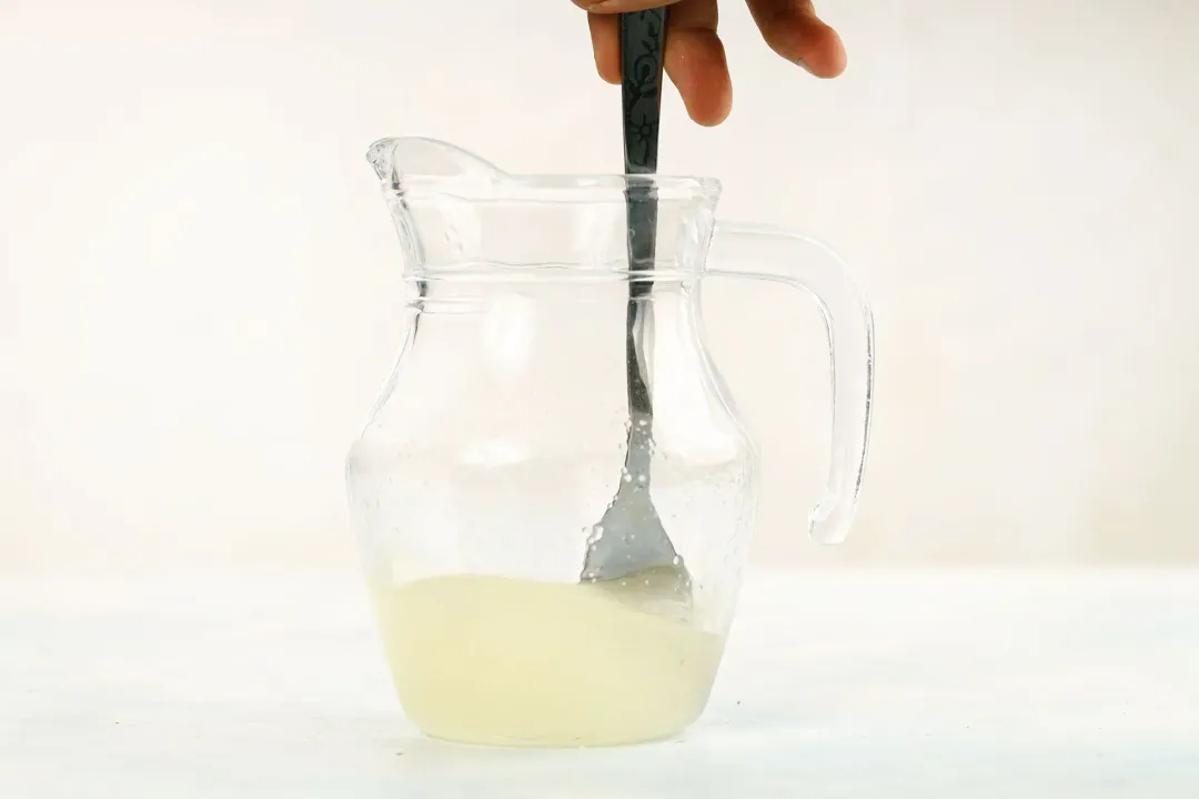 Stirring a cute pitcher of lime juice with a metal spoon