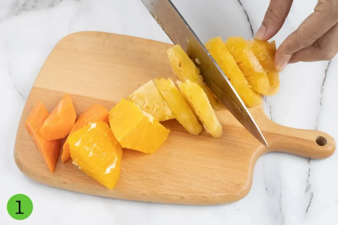 Cutting carrots, oranges, and pineapples on a wooden cutting board