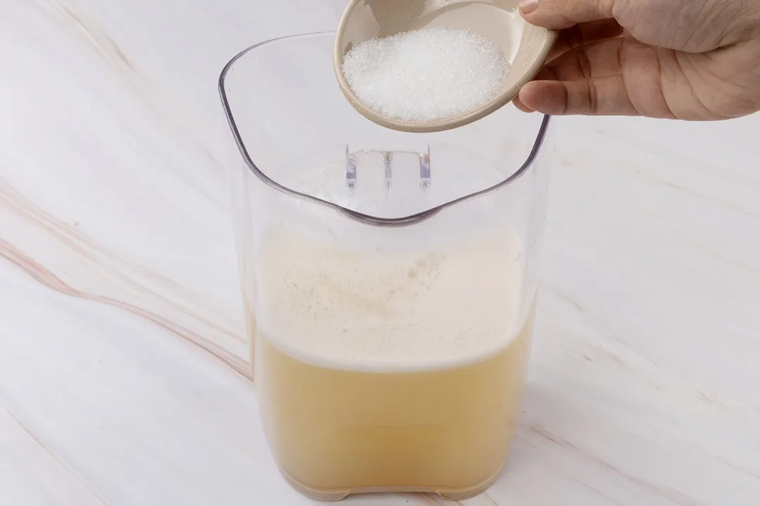 pouring sugar from a small bowl to a juice pitcher