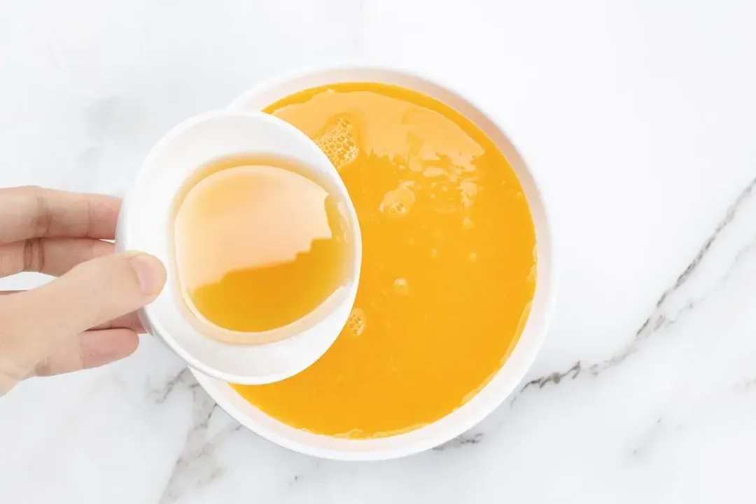 Pouring some honey into a bowl of orange juice