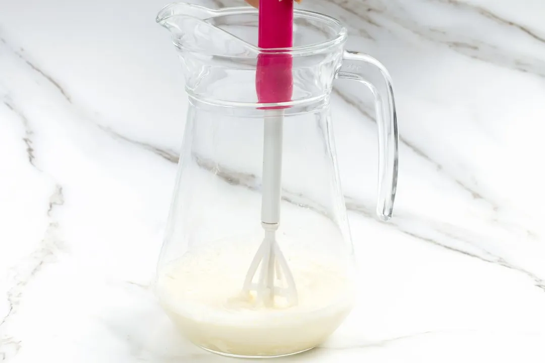 stirring milk mixture in a pitcher