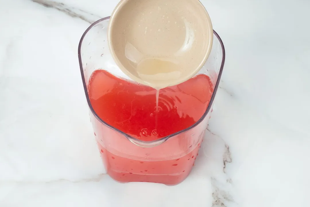 pouring lemon juice from small bow to a pitcher