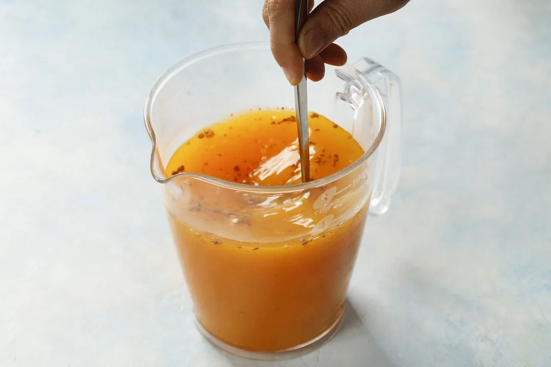 whisking yellow liquid in a pitcher by a spoon