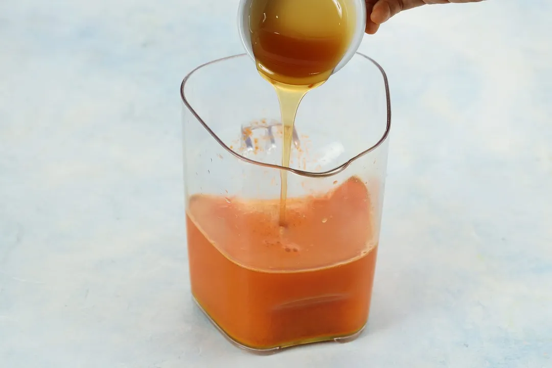 pouring honey from a small bowl into a pitcher