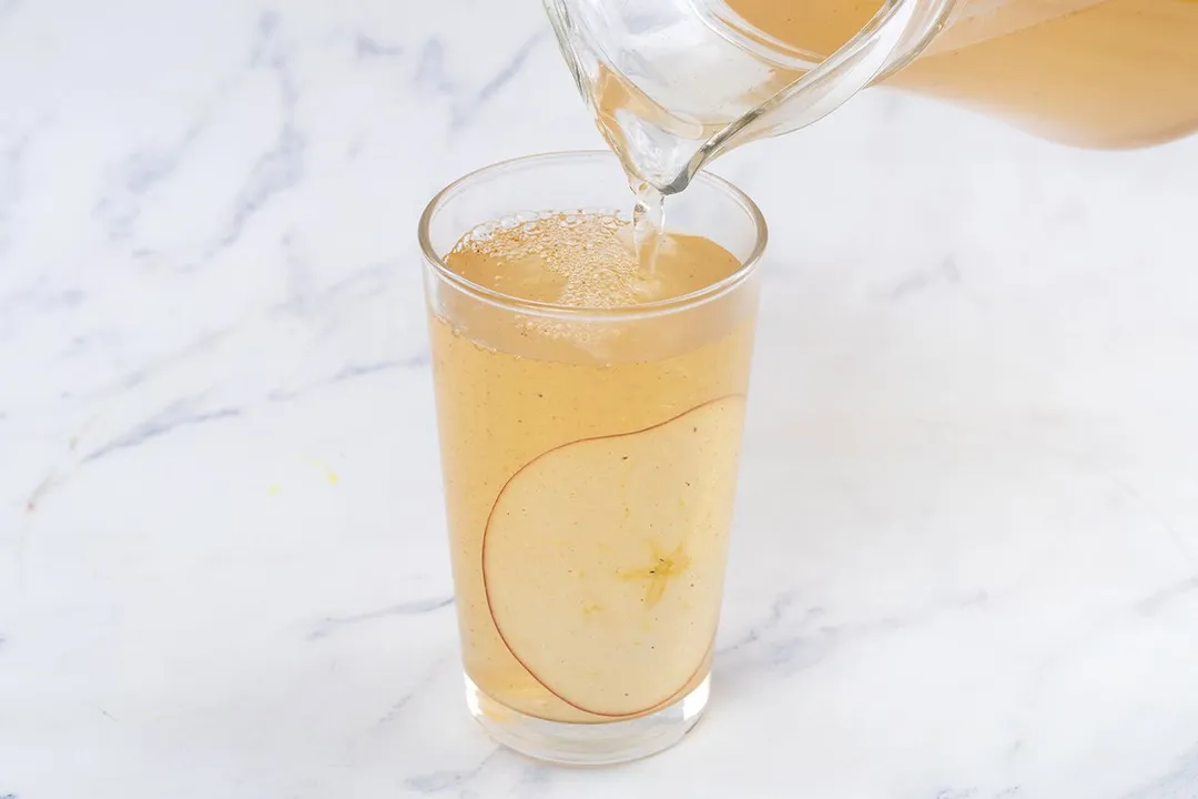 pouring apple cider vinegar and honey from a jar to glass