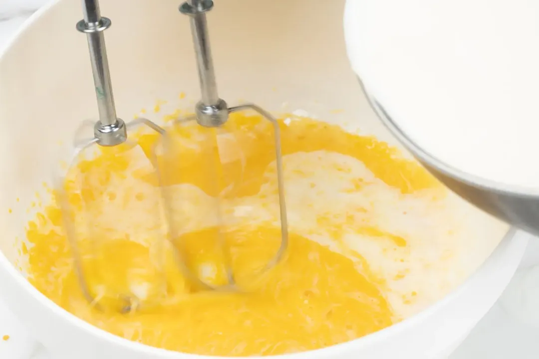 Whisking some mixture of eggnog inside a black pot
