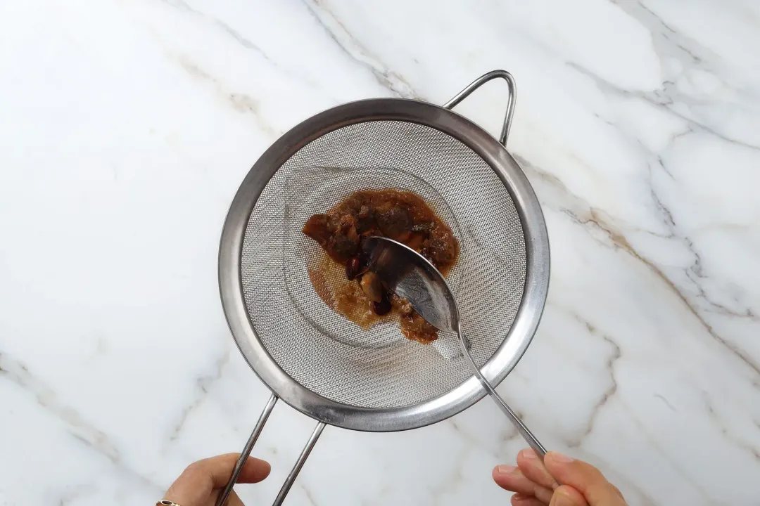 Tamarind pressed through a metal sieve with a metal spoon